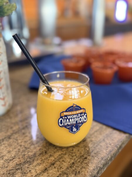 Glass on counter with bright yellow drink and black straw.