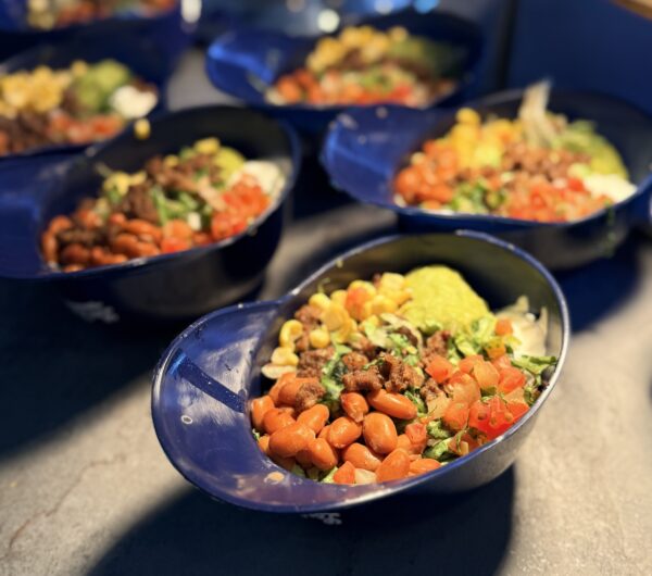 Veggie burrito bowls in plastic Dodger caps on counter
