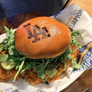 Chicken sandwich in a bun marked with LA Dodgers logo.