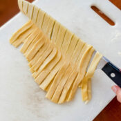 Knife lifting homemade tagliatelle noodles.