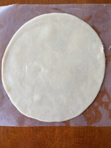 Unbaked pie dough circle on waxed paper.