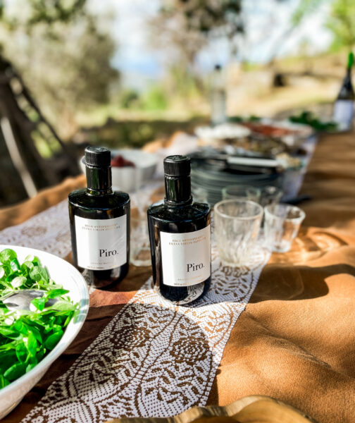 Olive oil bottles and salad on picnic table.