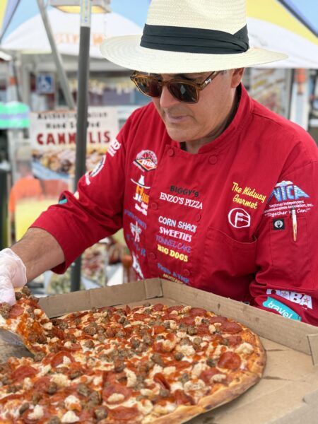 Man holding pizza box and taking a slice of pizza.