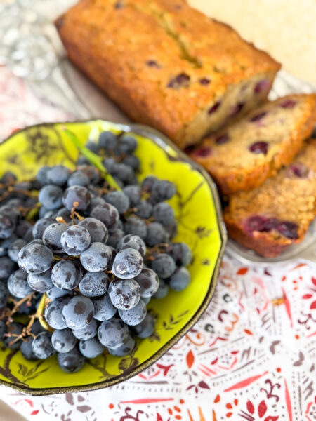 Closeup of grapes in a bowl with banana bread in the background.