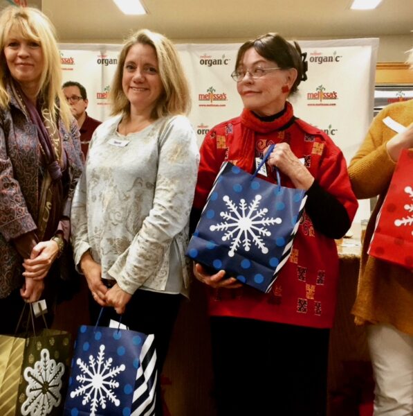 Three women holding gift bags. 