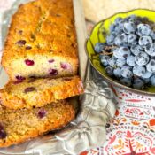 Loaf of banana bread next to bowl of grapes.