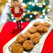 Cookies on silver platter next to holiday nutcracker.
