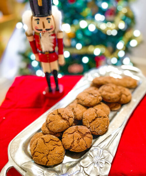 Cookies on silver platter next to holiday nutcracker.