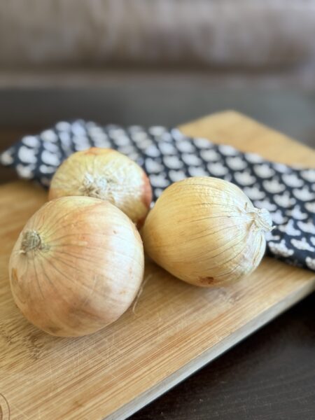 Three onions on a cutting board.
