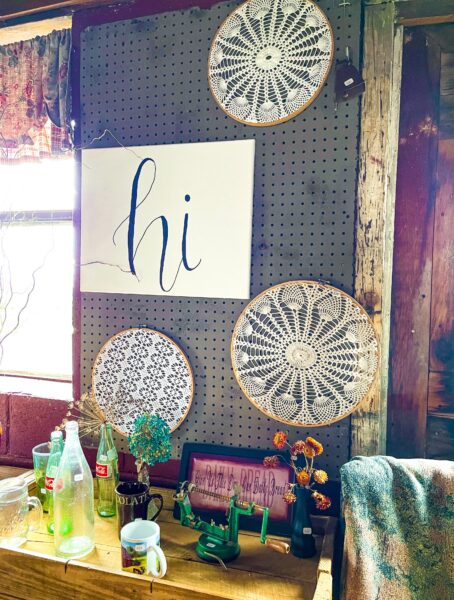 Wall display with embroidery and artwork that says hi.