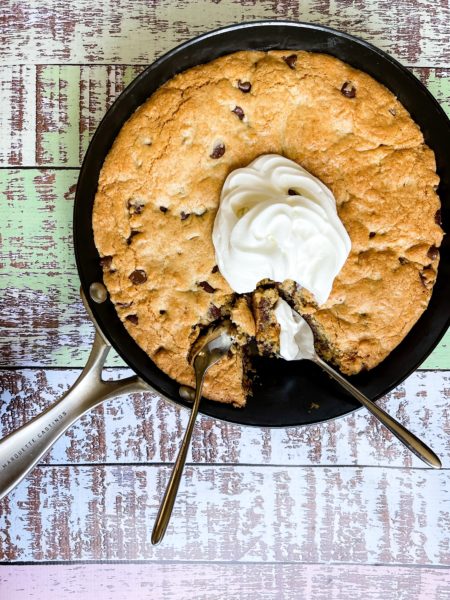 Two spoons in a skillet of chocolate chip bars.