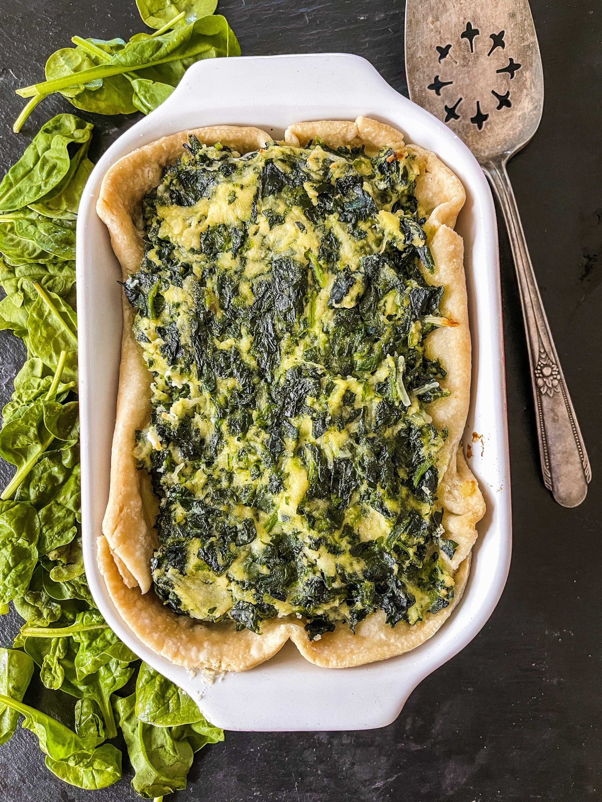 Overhead view of spinach pie with serving utensil.