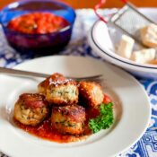 zucchini meatballs on plate with tomato sauce and cheese on table.